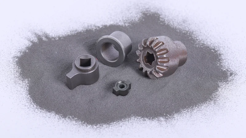 Gear parts sitting in a bed of metal powder.